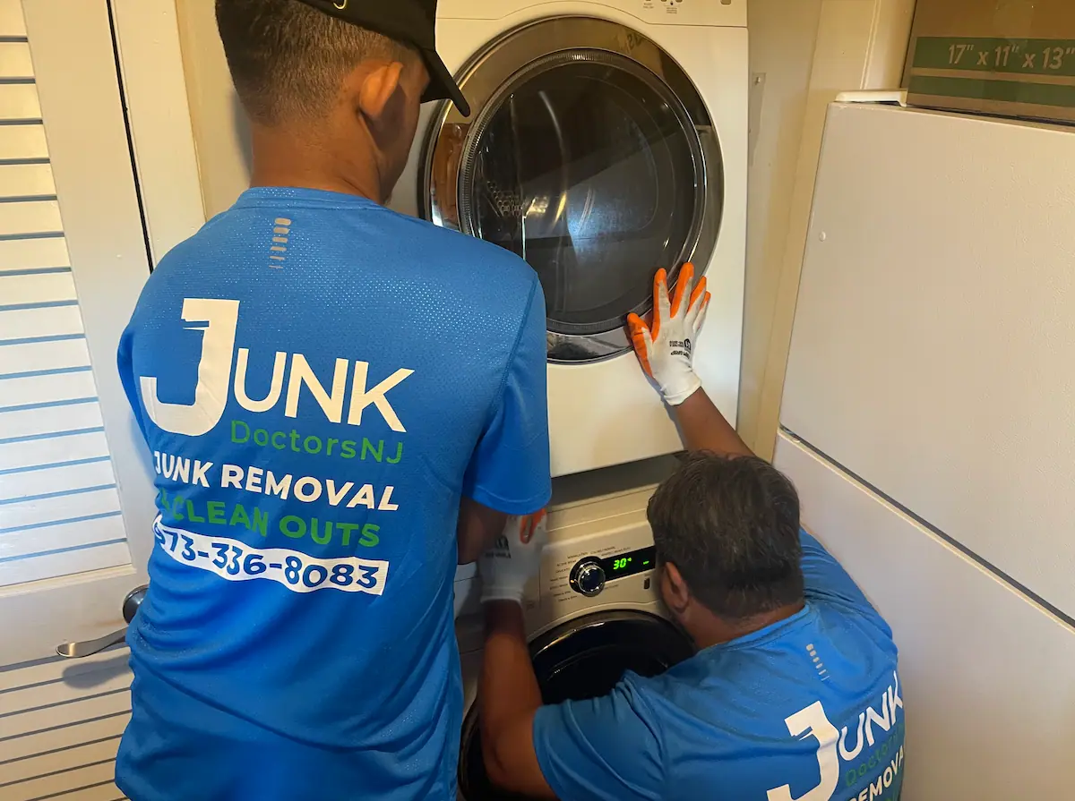 JunkDoctors crew safely disconnecting and removing a heavy stacked washer and dryer from a tight laundry closet in New Jersey.