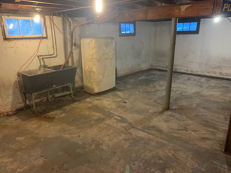 A basement cleared of all water-damaged junk and debris by the JunkDoctors NJ crew, showing a clean, bare concrete floor.
