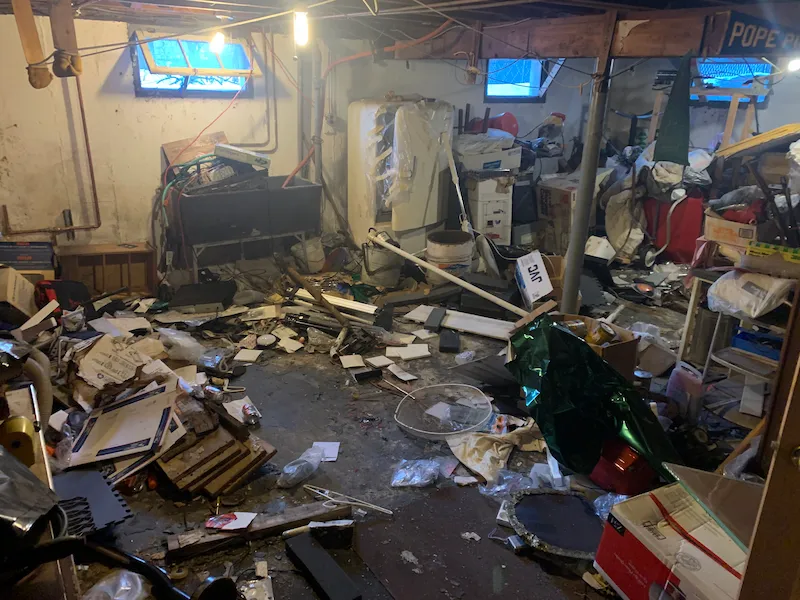 Water-damaged household items and messy storage in a basement before professional removal and hauling in North Jersey.