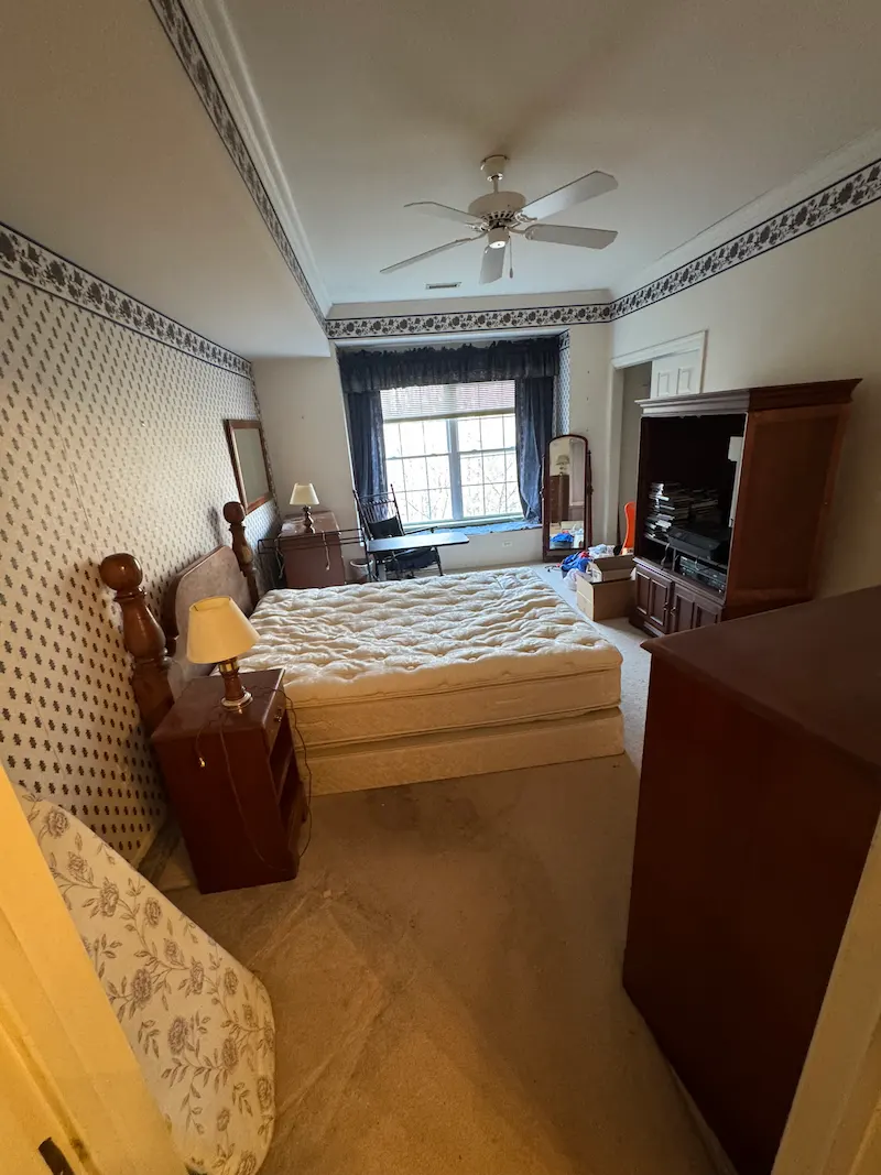 Full bedroom set including a large wooden armoire, mattress, box spring, and nightstands before professional furniture removal.