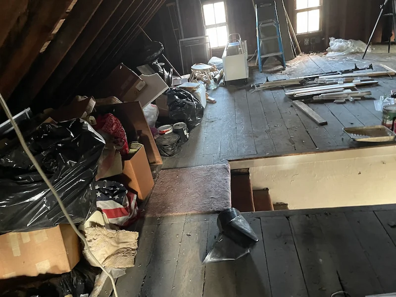 A cluttered attic space in Bridgewater, Central Jersey filled with stored boxes and old items before a JunkDoctors cleanout.