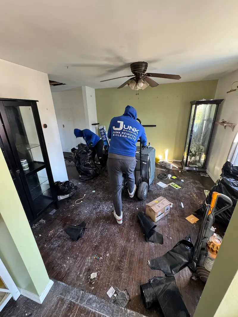 Junk Doctors NJ crew member using a hand truck to remove a dishwasher and household debris from a room during an appliance removal project.