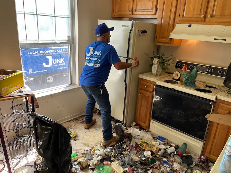 Professional junk removal specialist performing an emergency kitchen cleanout, removing an old refrigerator from a cluttered home