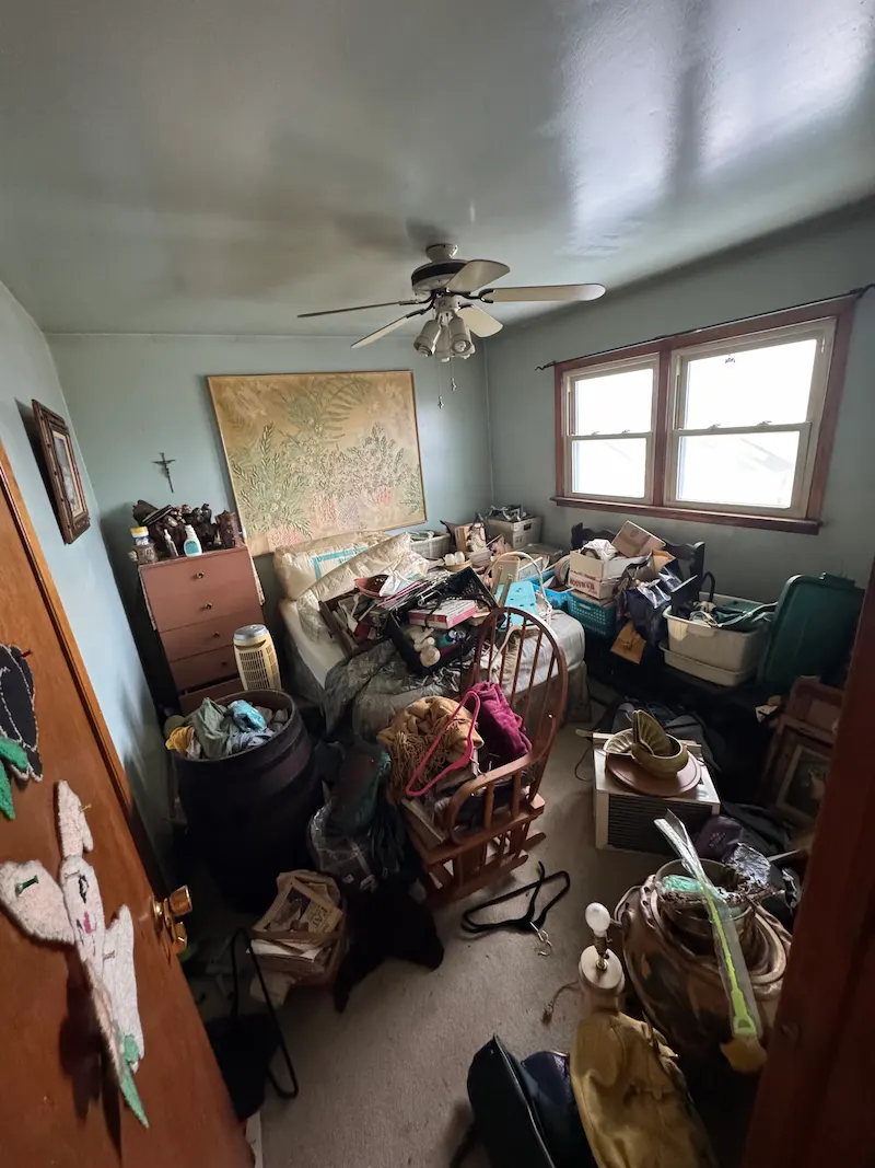 Room filled with tenant belongings, furniture, and garbage left behind after an eviction, before a professional cleanout.