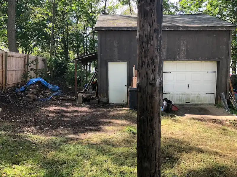 The same New Jersey backyard area completely cleared of hoarding debris and junk, showing the clean ground and shed area.