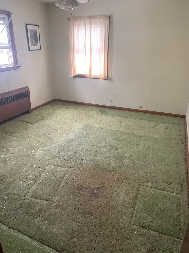 A Morristown, New Jersey bedroom completely empty and cleared of all hoarder junk and debris, showing the carpet and walls ready for renovation or cleaning.