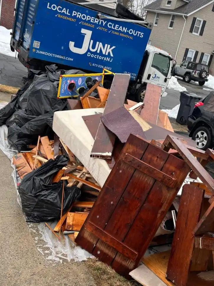 Emergency flood debris removal in North NJ showing a large pile of ruined household items and building materials being hauled away by Junk Doctors NJ.