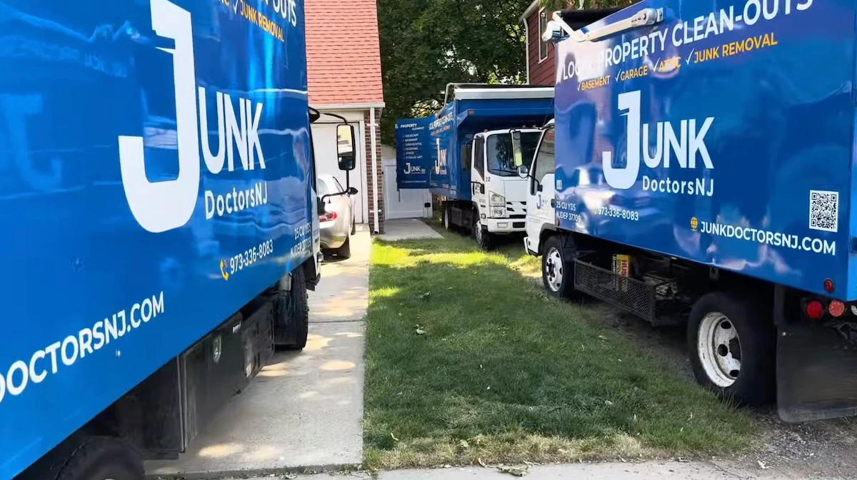 A fleet of three Junk Doctors removal trucks parked at a residential property, ready to perform a large-scale foreclosure cleanout in New Jersey.
