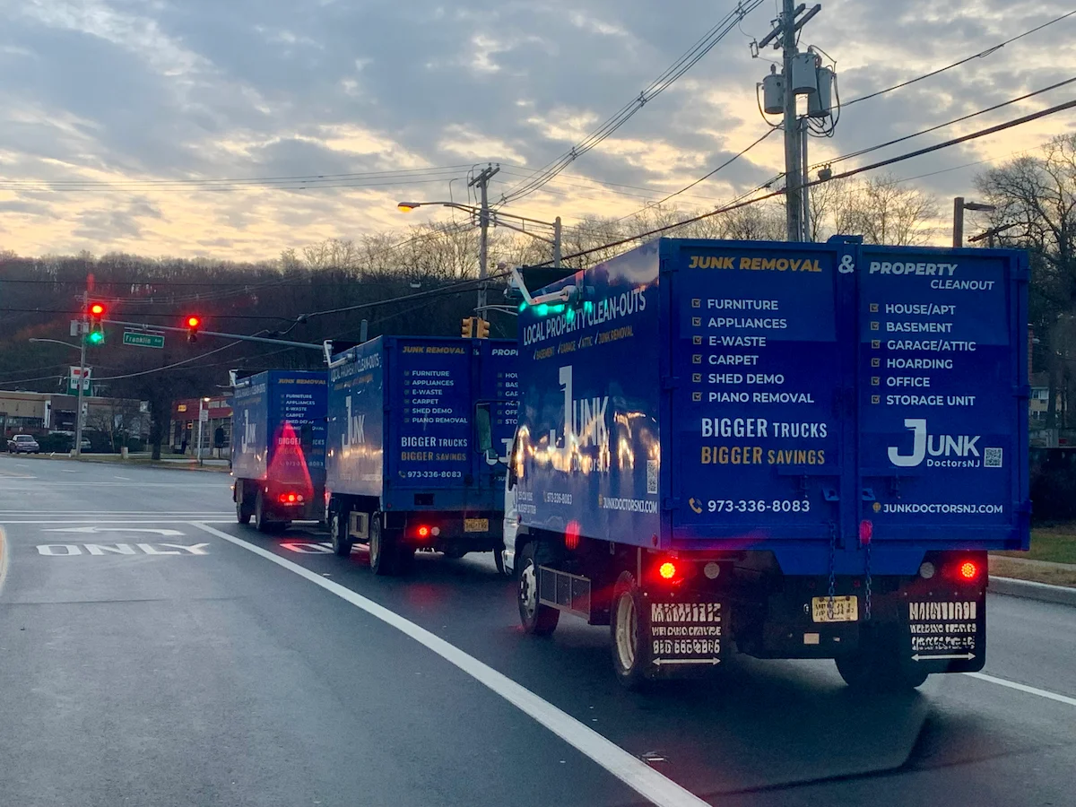A fleet of three professional JunkDoctors 25-cubic-yard trucks on a New Jersey road, showcasing the capacity for high-volume junk removal and property cleanouts.