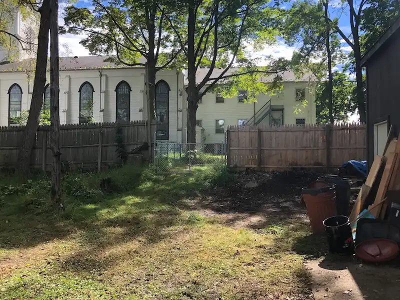 A completely cleared backyard area in North Jersey after a professional hoarding cleanup service, showing the grass and garage area free of debris.
