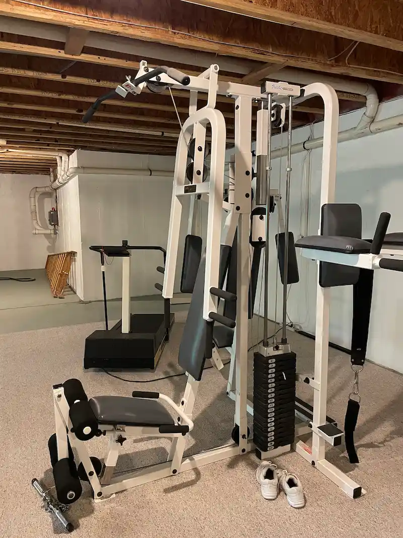 A large multi-station weight machine in a basement before being disassembled and removed by Junkdoctors NJ.