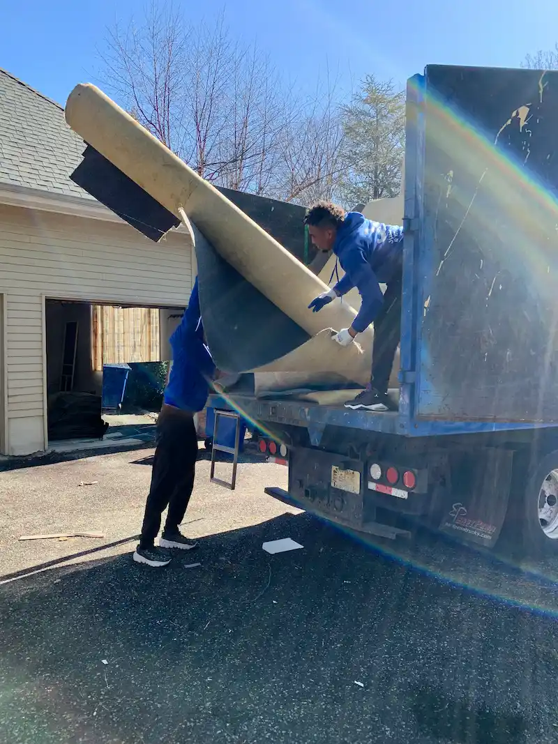 Two Junk Doctors NJ crew members hauling away old carpets and residential debris during a household junk removal project in North Jersey.
