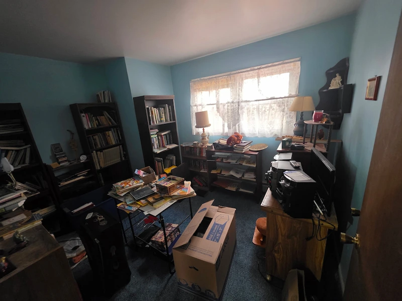 Before photo of a residential room filled with household junk, books, and boxes before being cleared by Junk Doctors NJ.