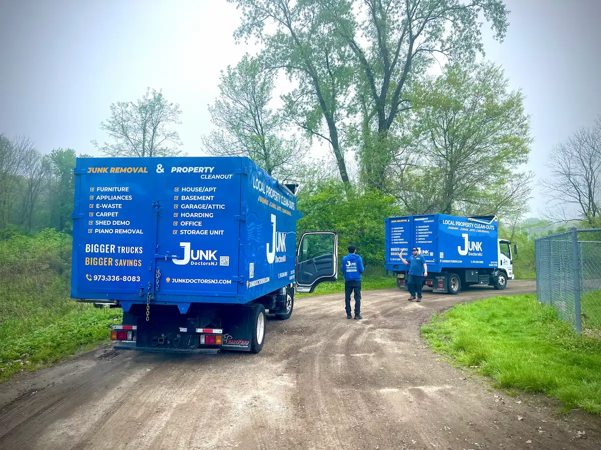 Two JunkDoctors removal trucks parked on a dirt path for a large residential yard debris cleanup in New Jersey.