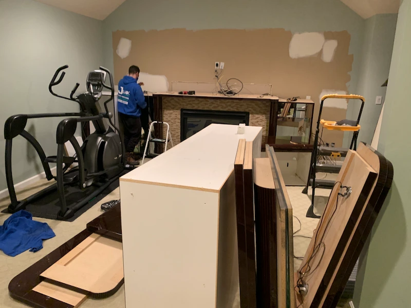 Junk Doctors crew member performing an interior local cleanout service in New Jersey, disassembling heavy furniture and clearing out a cluttered residential room.