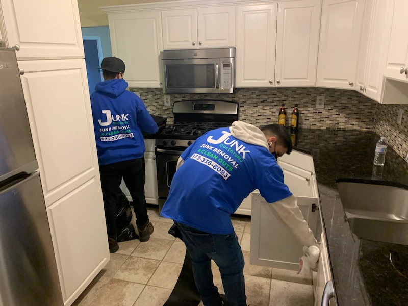 JunkDoctors crew clearing out cabinets and counters in a modern NJ kitchen during a full property cleanout.