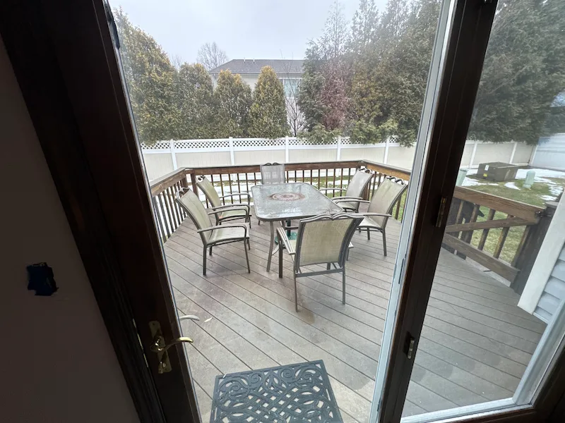 A backyard deck in NJ cluttered with an old glass table and patio chairs before a JunkDoctors yard cleanup and hauling service.