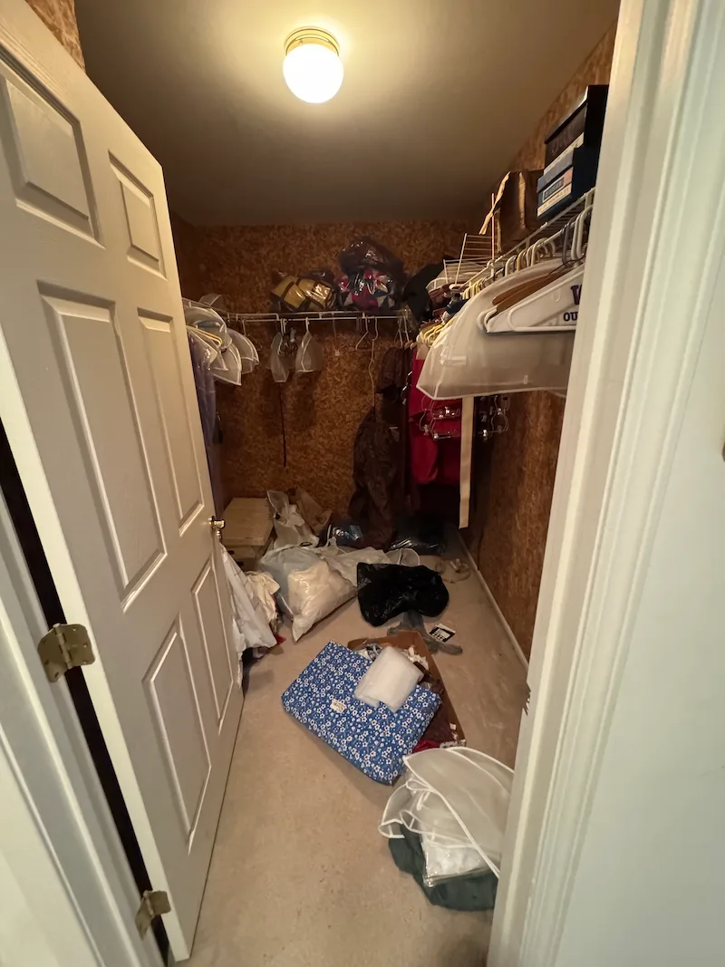 Messy walk-in closet in a foreclosure property with clothes and bags on the floor before a JunkDoctors NJ cleanout.