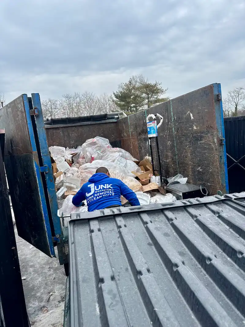 JunkDoctors NJ team member loading bags of commercial waste and retail debris into a large hauling truck during a store cleanout project in North NJ.