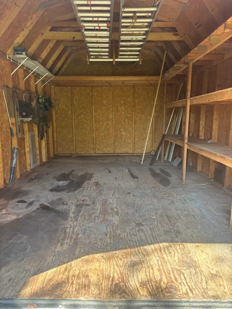 Interior of an Edison, New Jersey storage shed cleared of junk and debris by JunkDoctors, showcasing reclaimed floor space while functional items like overhead ladders remain.