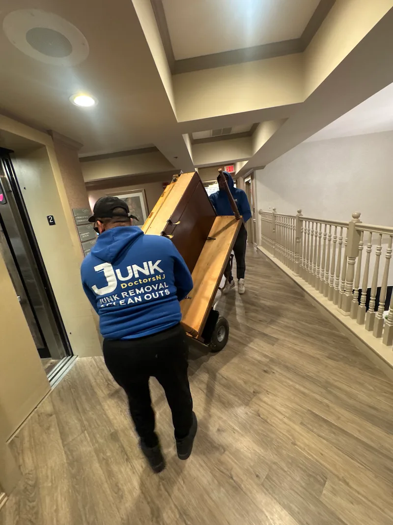 Specialized Junk Doctors NJ crew using a professional piano dolly to safely transport a heavy upright piano through a facility hallway in North NJ.