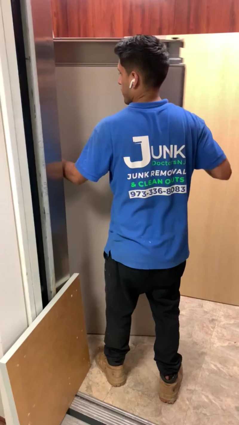 A JunkDoctors NJ team member carefully moving a large wooden panel out of a storage facility elevator during a cleanout.