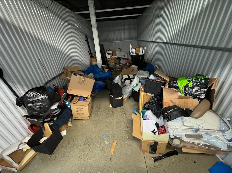 Before photo of a cluttered self-storage unit in North NJ filled with boxes, bags, and household junk before being cleared by Junk Doctors NJ.