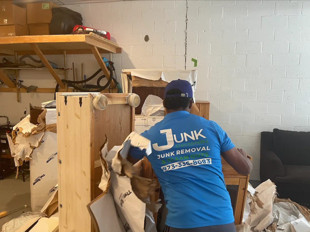 JunkDoctors crew member clearing out old furniture and packing debris from a storage unit in New Jersey.