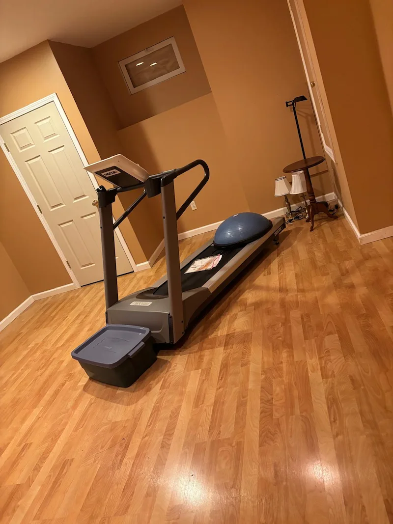 Heavy Precor treadmill sitting in a finished basement before being removed by JunkDoctors NJ.