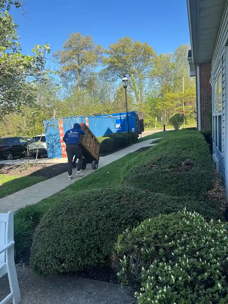 A uniformed Junk Doctors NJ professional carefully wheeling an upright piano down a sidewalk on a dolly for specialty removal in North Jersey.