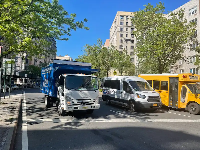 JunkDoctors truck navigating a busy residential city street for a high-rise apartment cleanout in New Jersey.