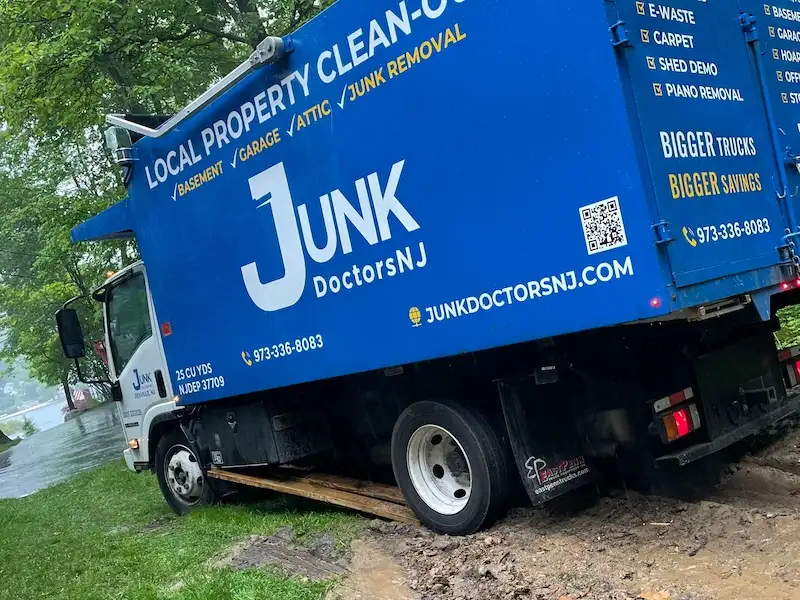 Junk Doctors NJ using protective boards to prevent lawn damage while hauling away water-damaged furniture and carpet.