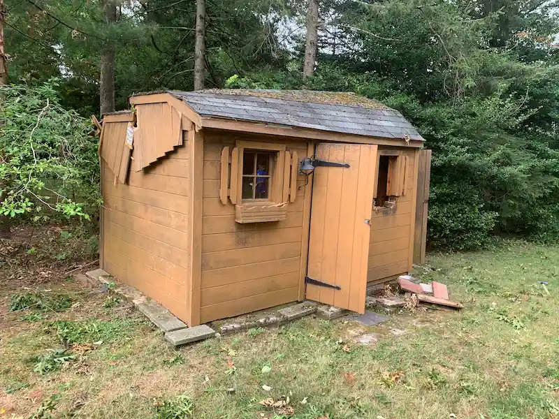 Before photo: An old, dilapidated wooden shed with a rotting roof in a New Jersey backyard, ready for professional demolition and hauling by Junk Doctors.