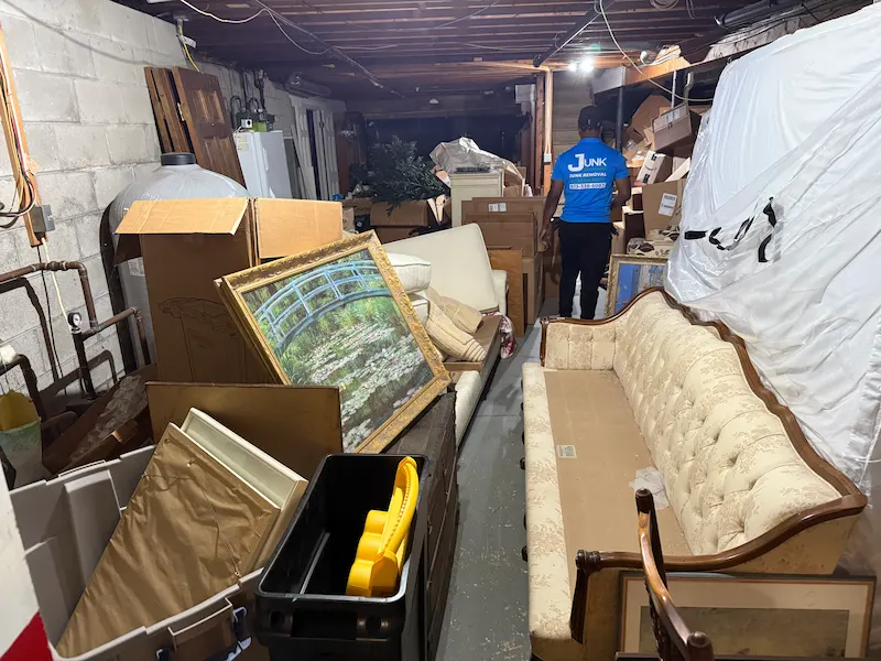 Crew member clearing furniture and boxes from a basement.