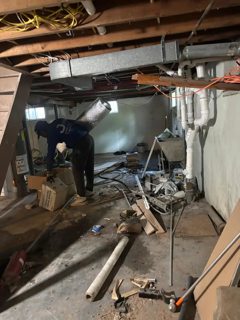 Crew member removing debris from a basement cleanout.