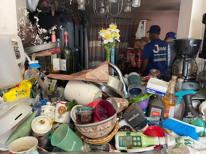 JunkDoctors crew moving through a heavily cluttered kitchen during a hoarding cleanout in New Jersey.