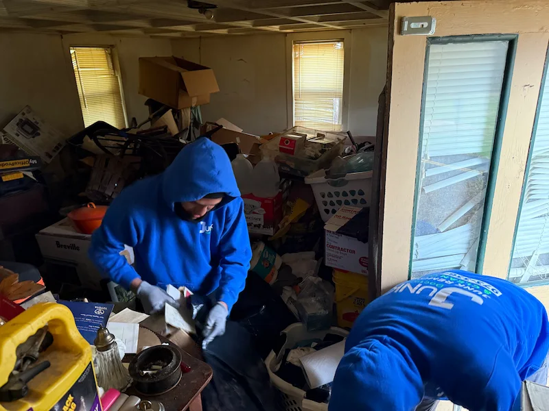 JunkDoctors team member bagging household items and clearing severe clutter during a residential trash-out.