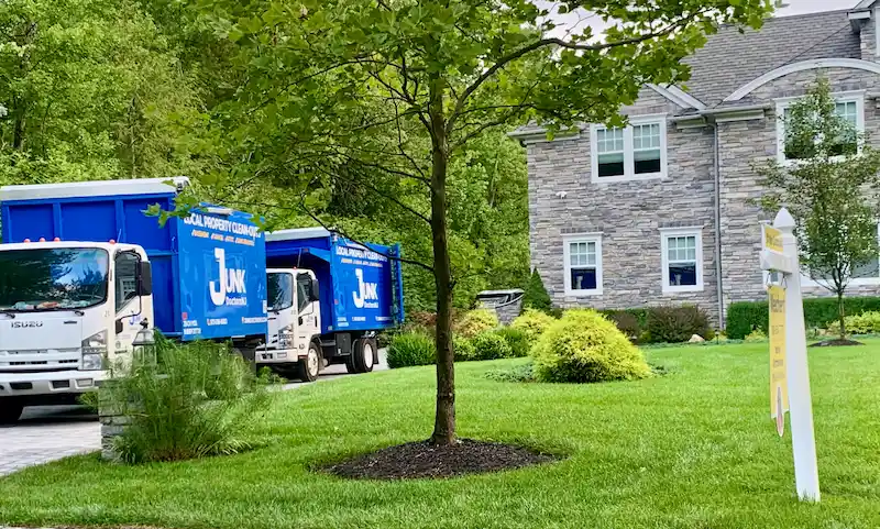 A fleet of two Junk Doctors NJ removal trucks arriving at a large luxury residential estate for a comprehensive property cleanout.